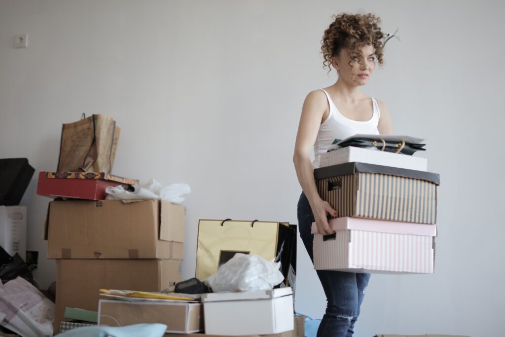 An image of a woman carrying boxes in her home.