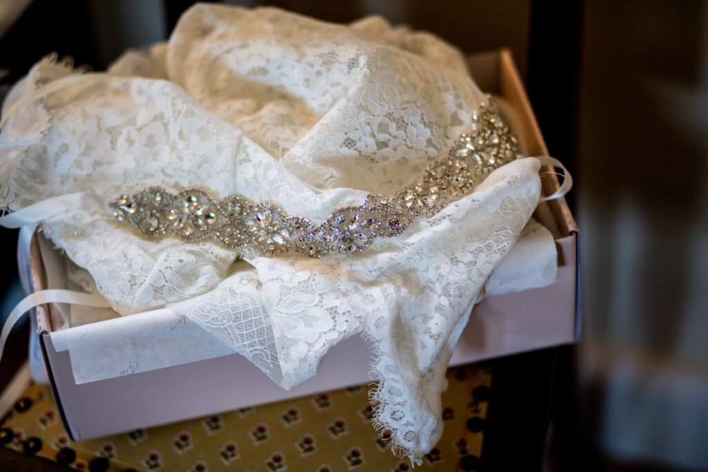 Close-up of a delicate lace bridal veil with intricate beaded trim in a box, perfect for weddings.